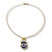 Gold necklace with a blue and black pendant on a white background