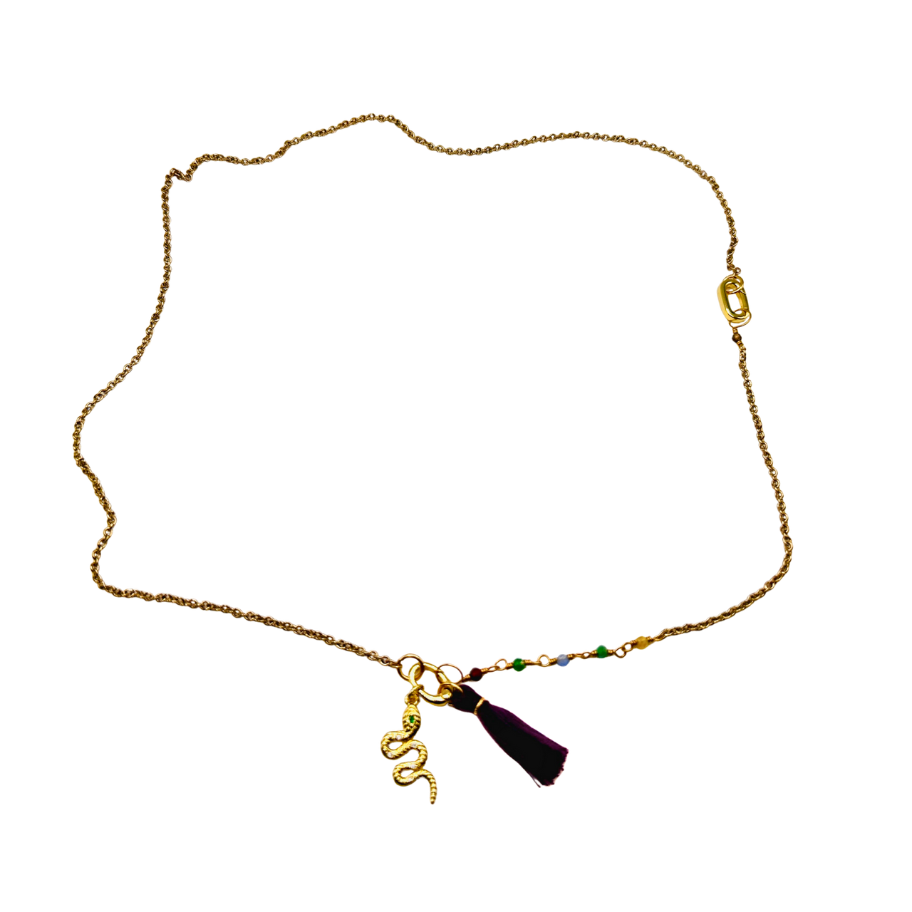 Gold necklace with a tassel charm on a white background