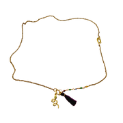 Gold necklace with a tassel charm on a white background