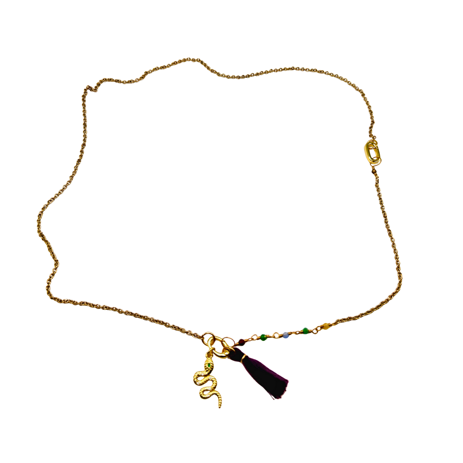 Gold necklace with a tassel charm on a white background