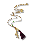 Gold necklace with a purple tassel pendant on a white background