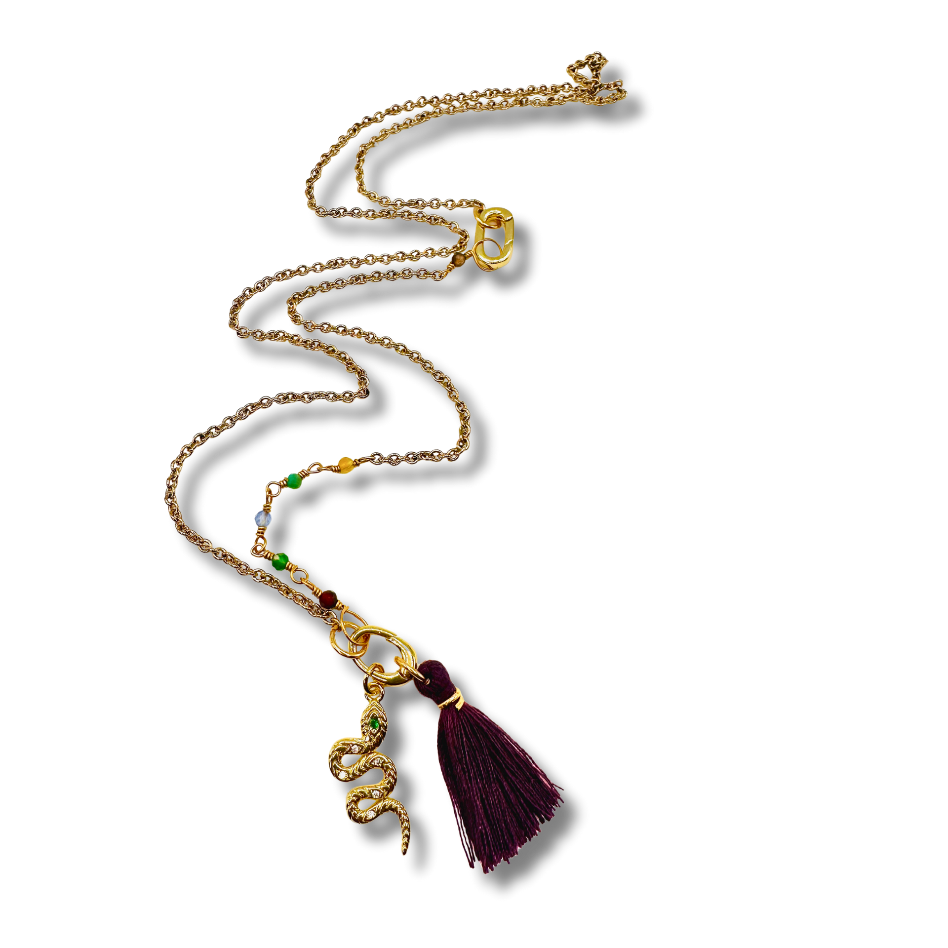 Gold necklace with a purple tassel pendant on a white background