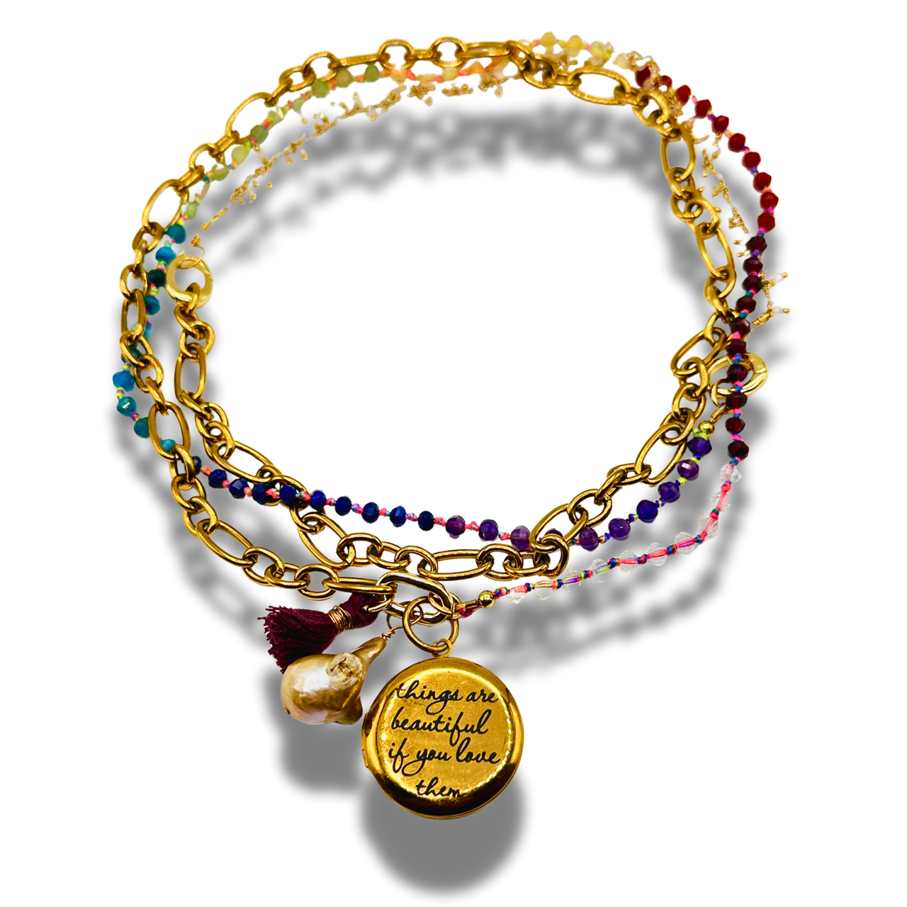 Stack of gold and beaded bracelets with a quote charm on a white background