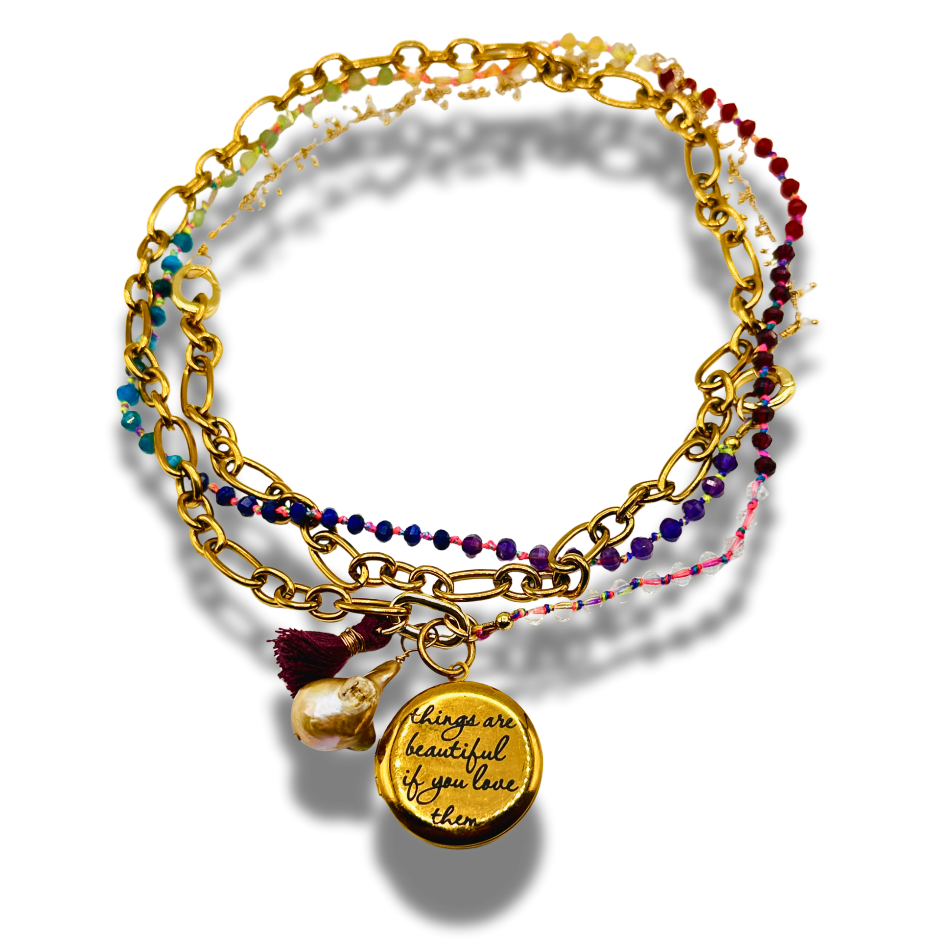 Stack of gold and beaded bracelets with a quote charm on a white background