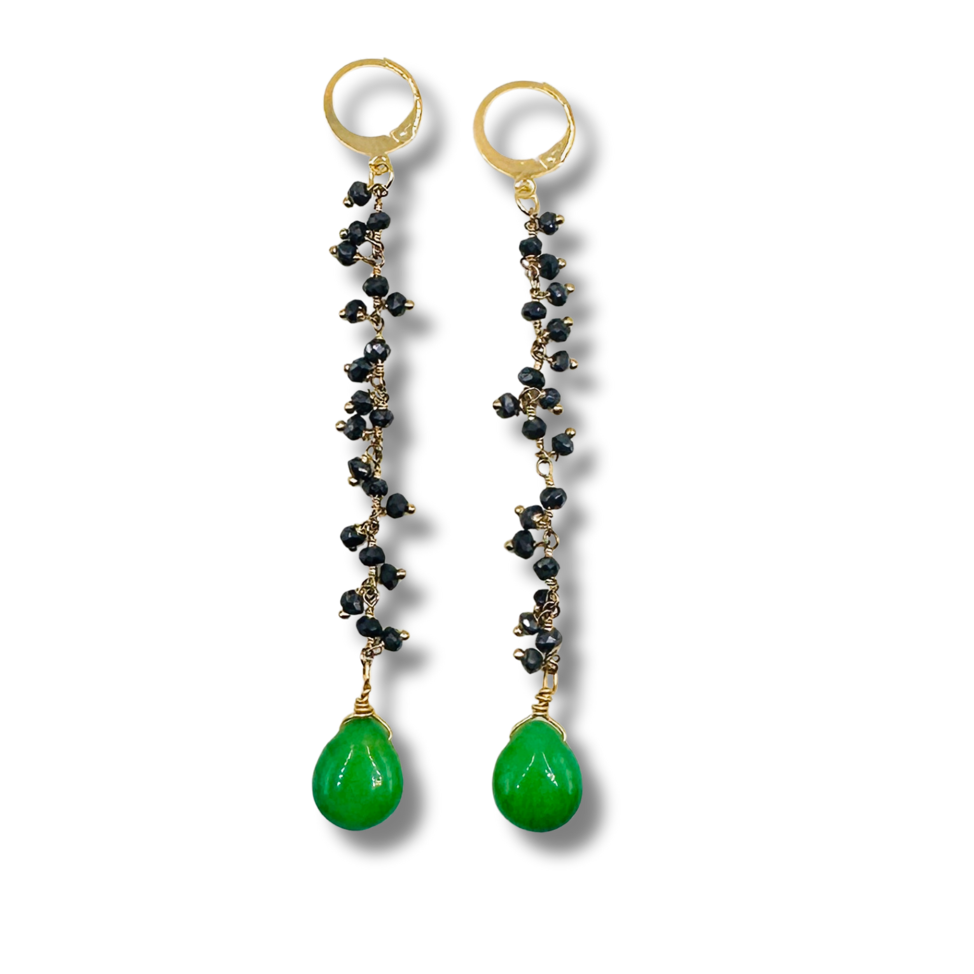 Pair of earrings with black beads and green teardrop stones on a white background