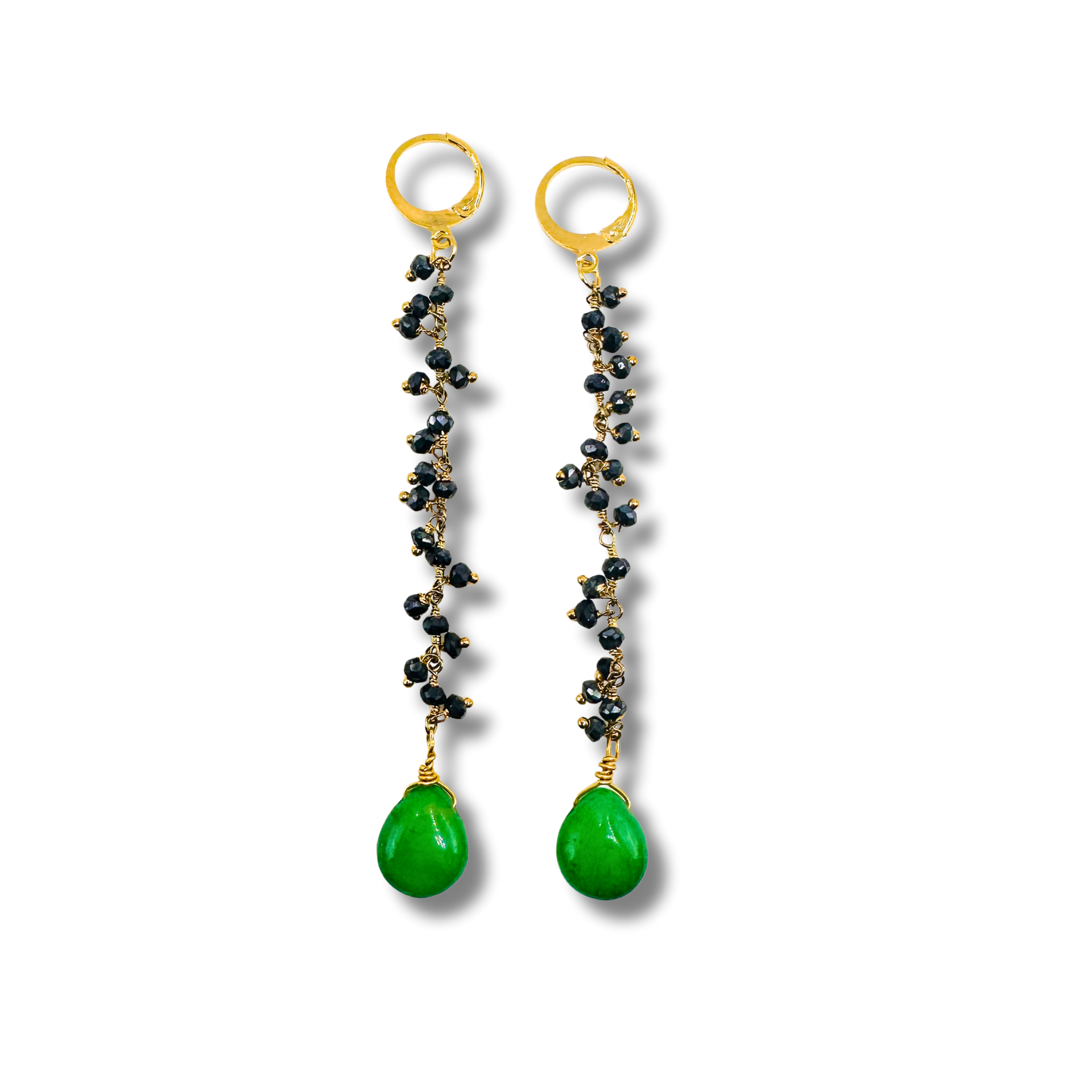 Pair of earrings with gold loops, black beads, and green teardrop stones on a white background