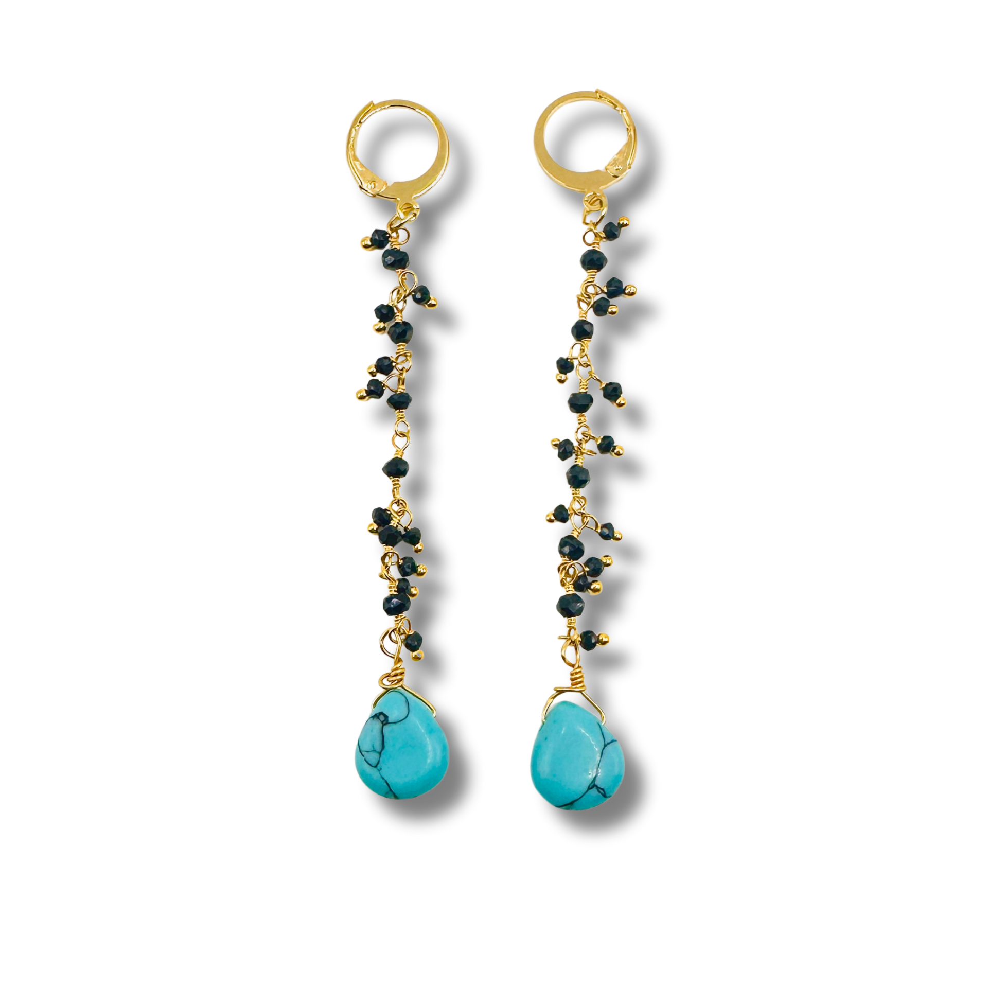 Pair of earrings with gold and black bead chains and turquoise stones on a white background