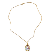 A gold chain necklace with a teardrop-shaped pendant containing a colorful, iridescent purple and green inlay, set against a plain white background.
