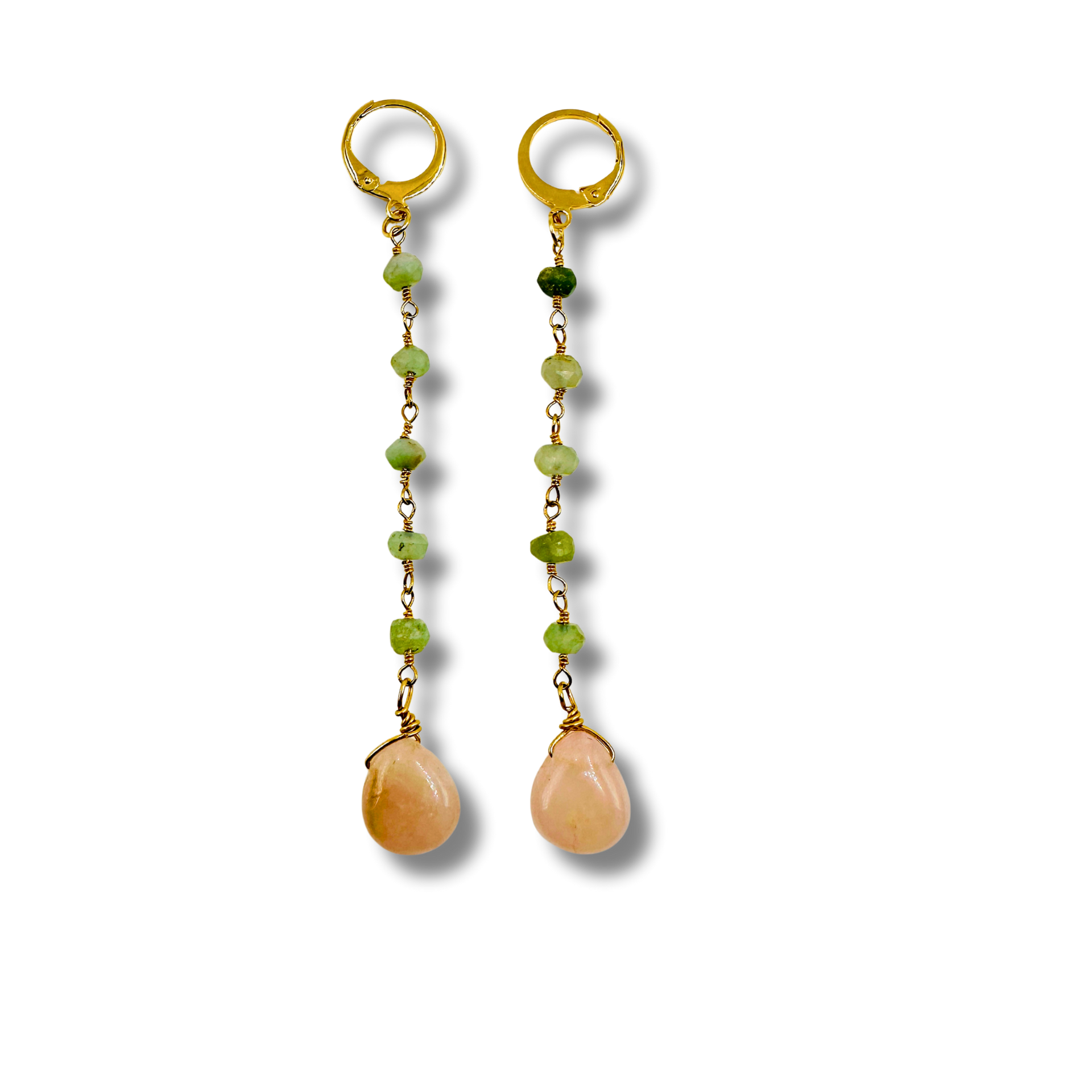 Pair of gold earrings with green beads and peach-colored teardrop stones on a white background