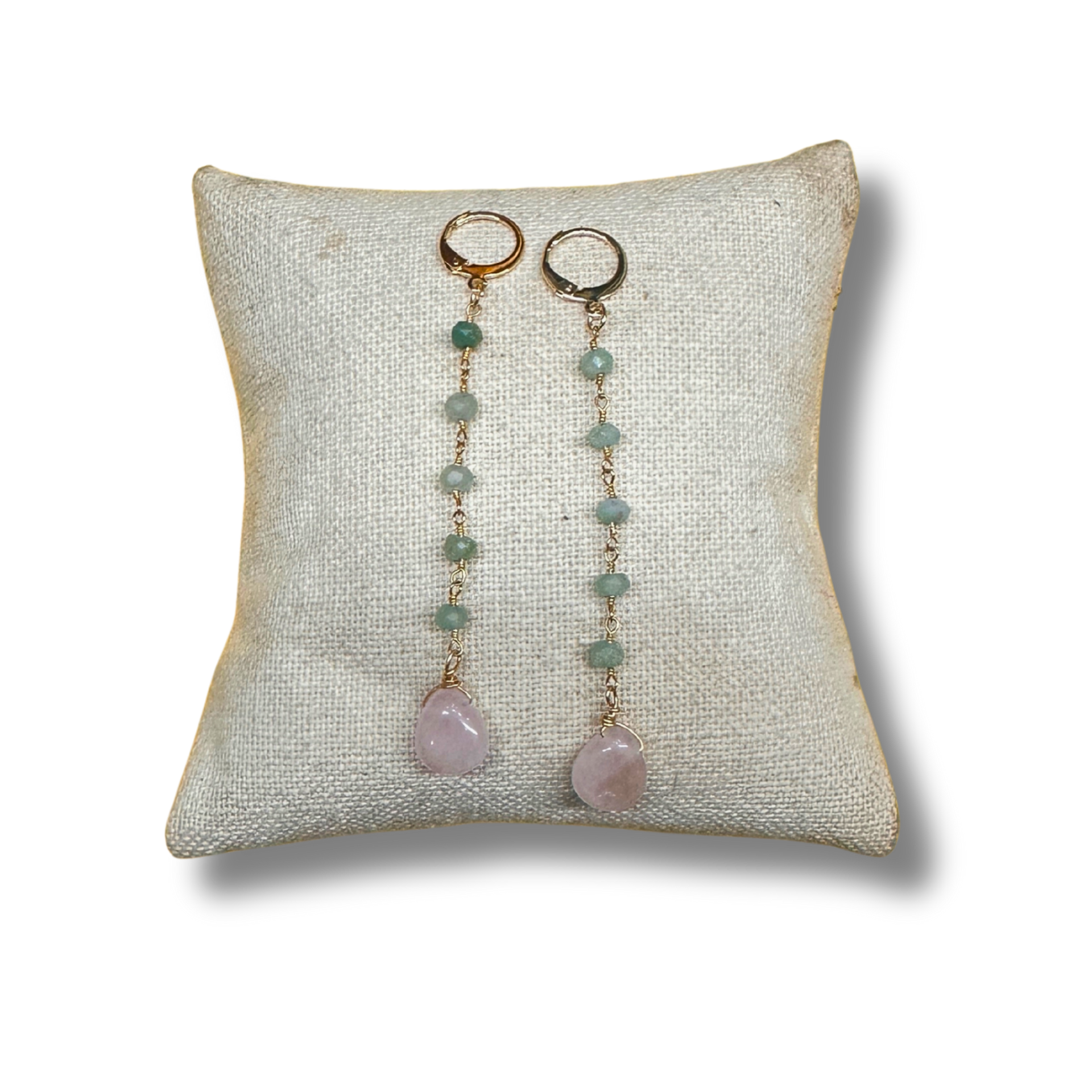 Pair of earrings with pink stones on a textured white pillow