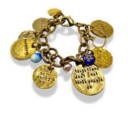 A gold-toned charm bracelet with multiple engraved round medallions, a blue and white bead, and a small blue floral charm, photographed on a white background.