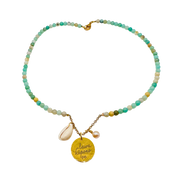 Beaded necklace with a yellow pendant and shell charm on a white background