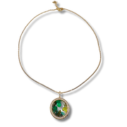 Gold necklace with a pendant featuring green gemstones on a white background