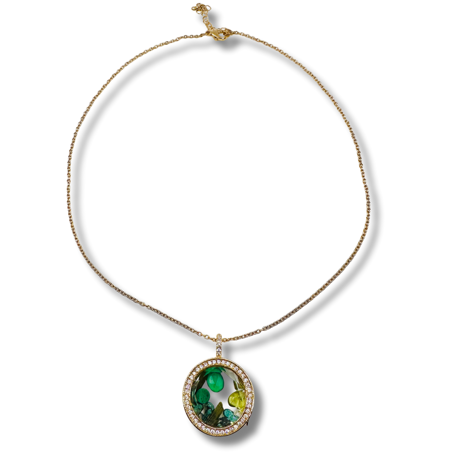Gold necklace with a pendant featuring green gemstones on a white background