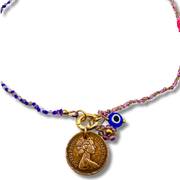 Necklace with various charms including a coin, blue evil eye, and floral elements on a white background