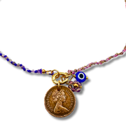 Necklace with a vintage coin charm and blue evil eye charm on a white background