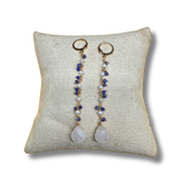 Pair of earrings with beads and stones on a textured pillow