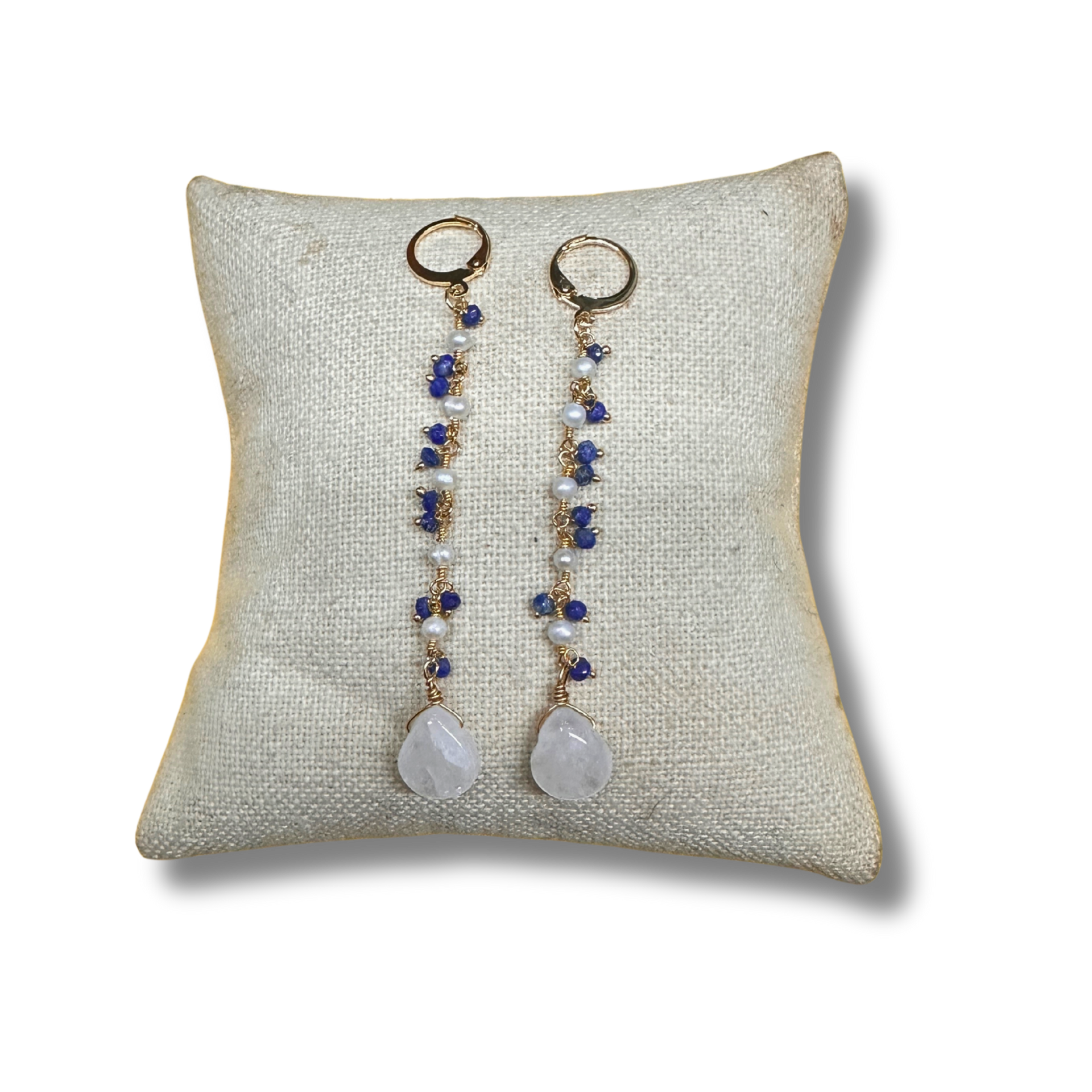Pair of earrings with beads and stones on a textured pillow