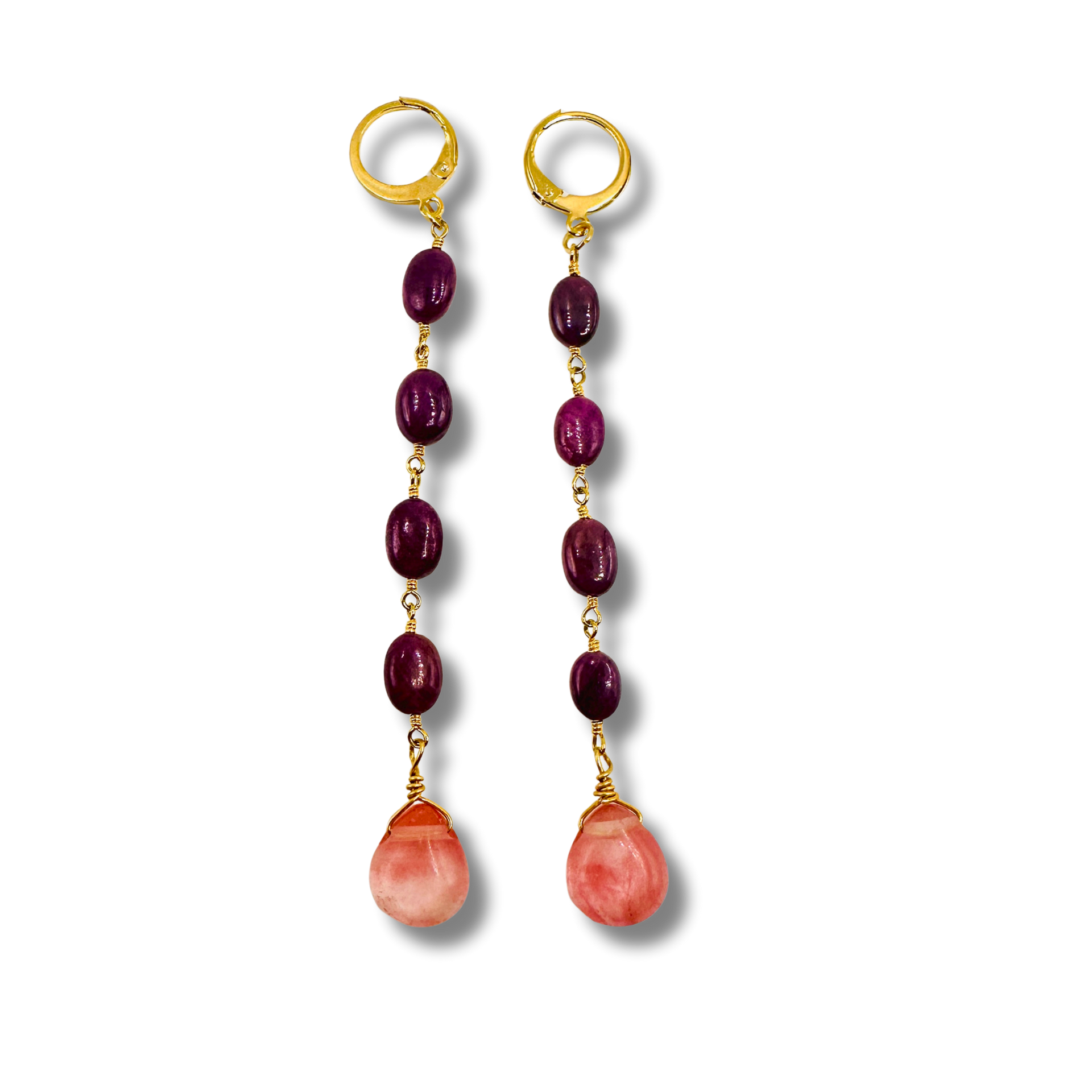 Pair of earrings with gold hooks, purple beads, and pink stone drops on a white background