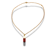 Gold necklace with a cylindrical pendant on a white background