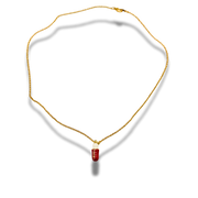 Gold necklace with a red pendant on a white background