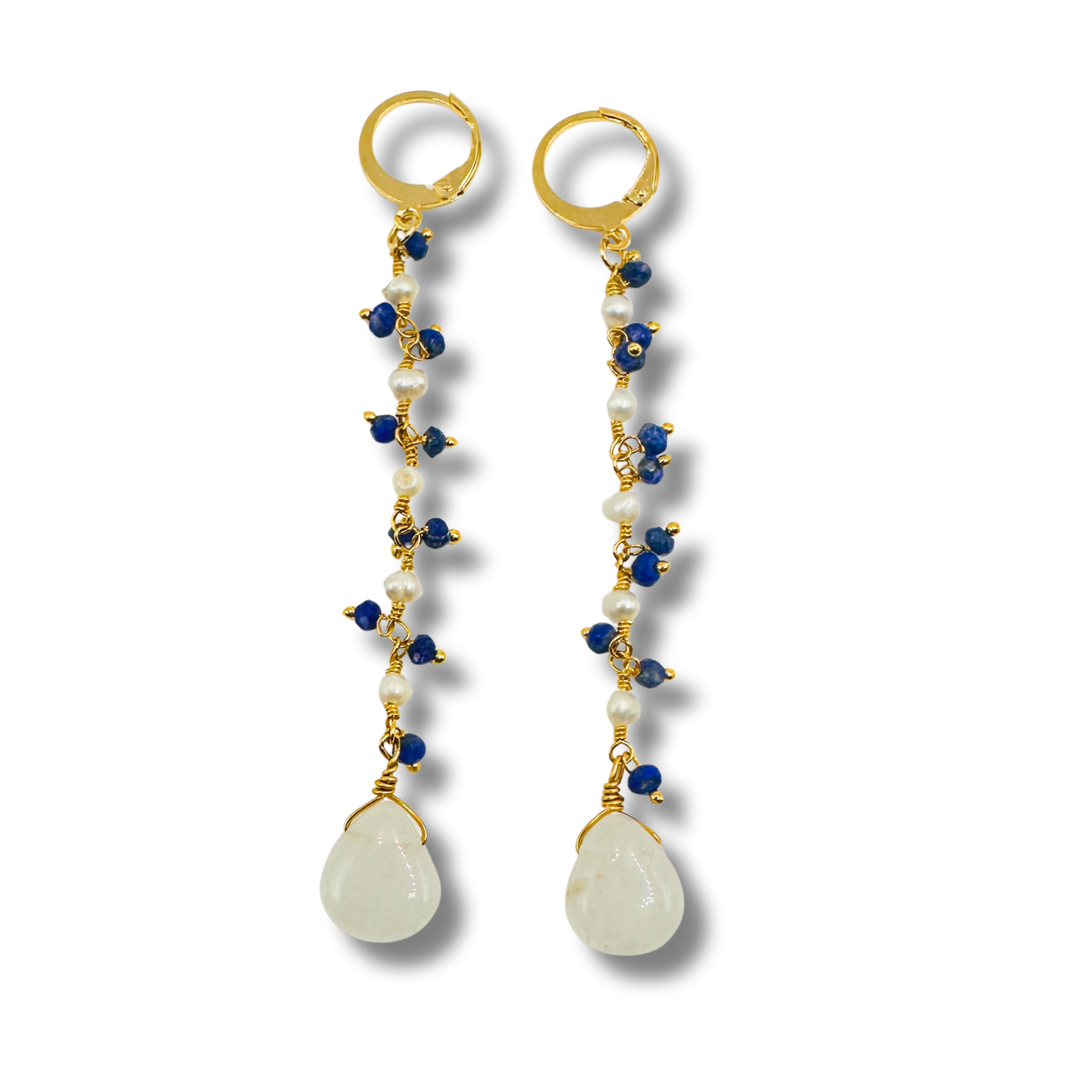Pair of earrings with gold hooks, blue beads, white stones, and gold loops on a white background