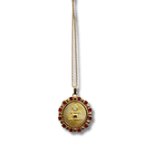 Gold necklace with a circular pendant featuring text and red stones on a white background
