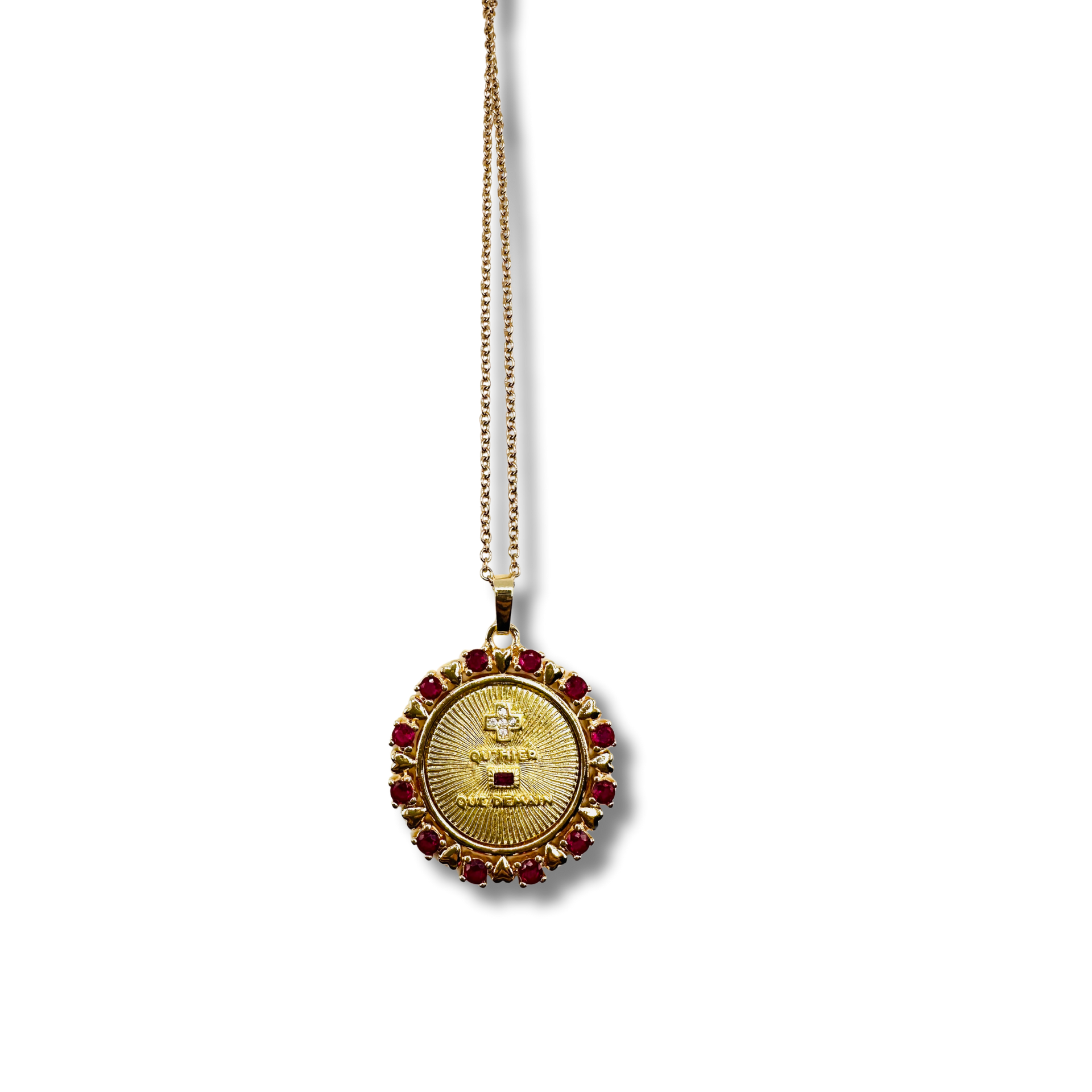 Gold necklace with a circular pendant featuring text and red stones on a white background