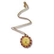 Gold necklace with a round pendant featuring red stones on a white background