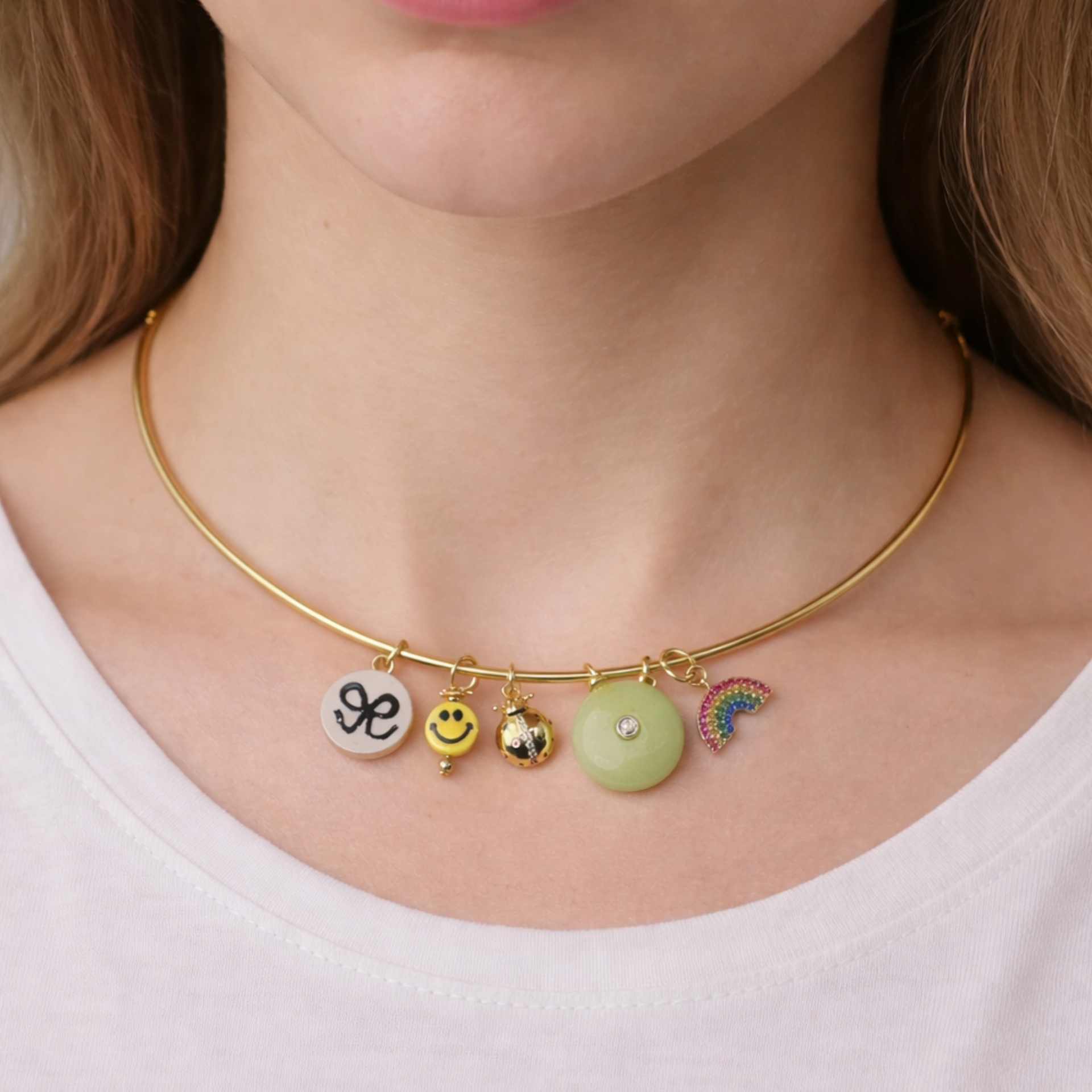 Playful 16" gold-tone collar necklace featuring a smiley face, rainbow, jade donut stone, lucky charms, and enamel details. Lightweight statement jewelry.
