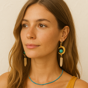 Woman wearing gold earrings with turquoise stones against a neutral background