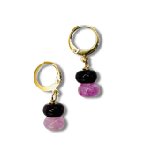 Pair of gold hoop earrings with black and pink beads on a white background
