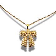 Gold necklace with a bow-shaped pendant on a white background