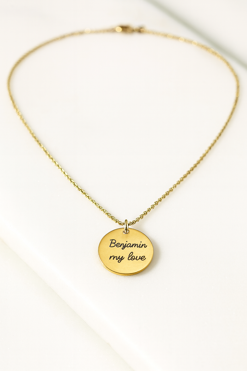 Gold necklace with a round pendant on a white background