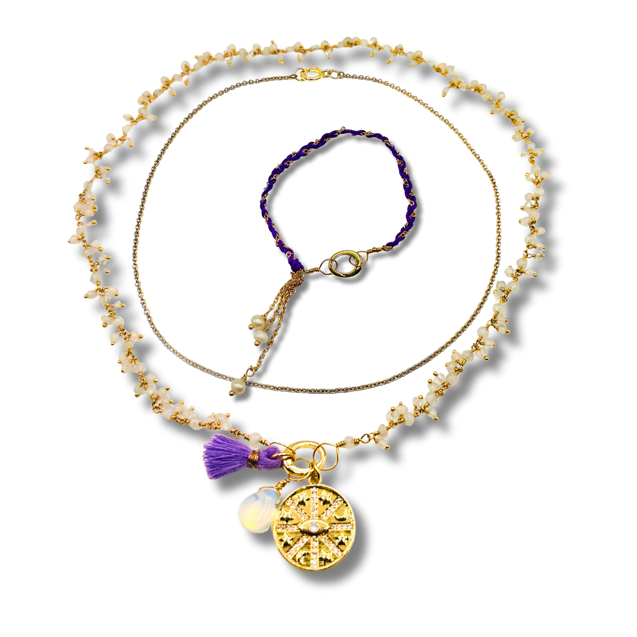 Gold necklace with a purple tassel and pendant on a white background
