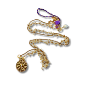 Gold necklace with various pendants on a white background