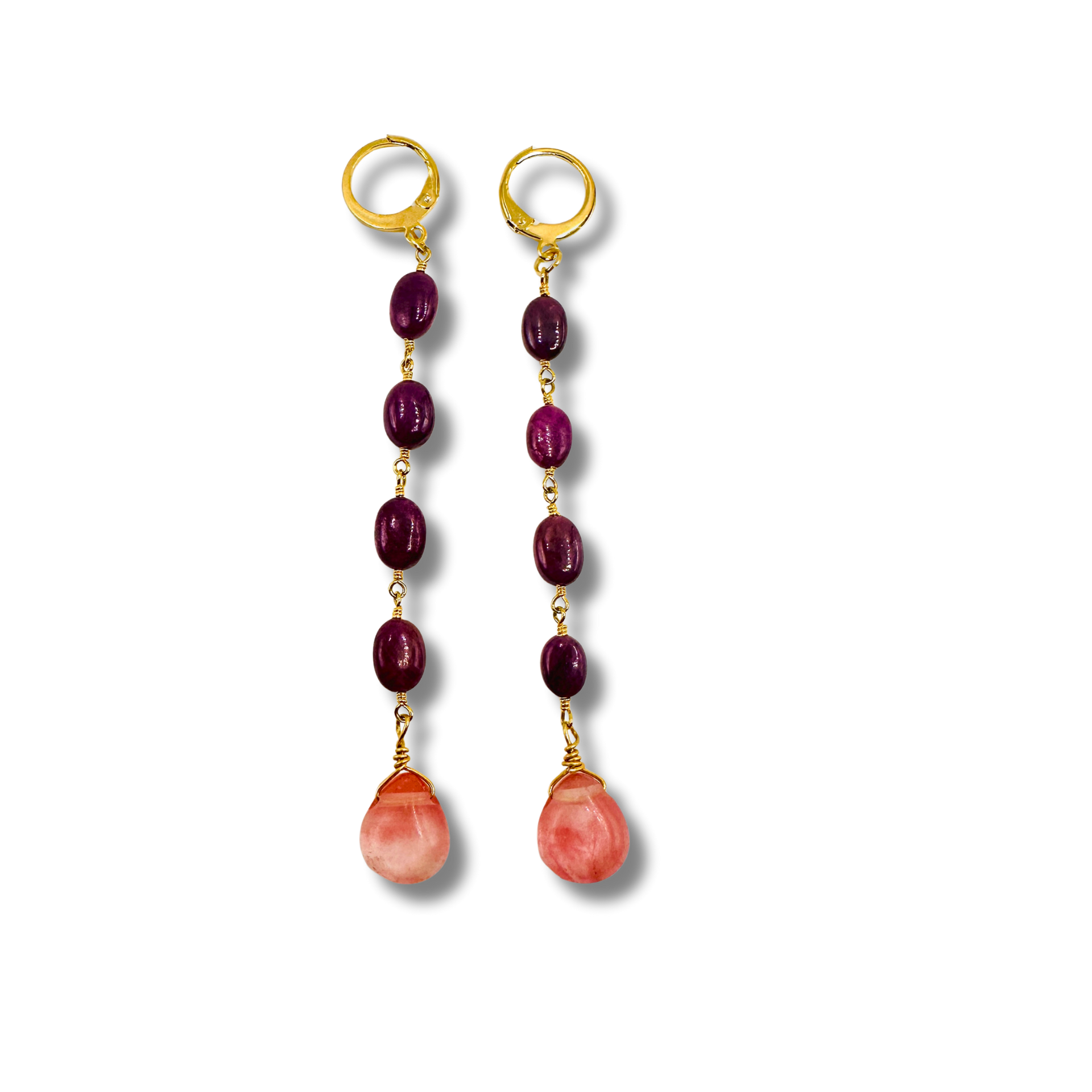 Pair of earrings with gold hooks, purple beads, and pink stones on a white background