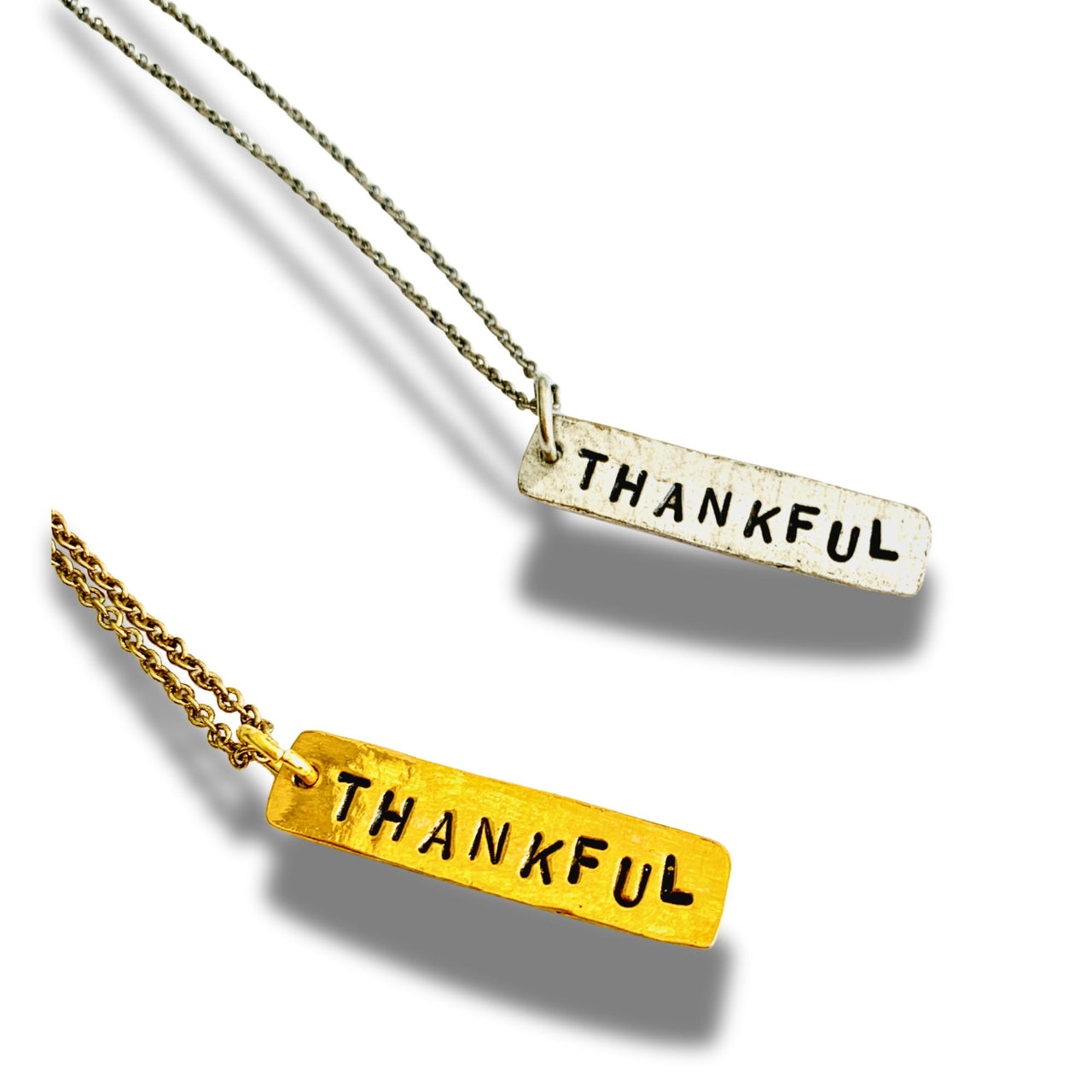 Two 'THANKFUL' necklaces, one gold and one silver, on a white background.