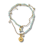 Necklace with beaded chain and gold pendants on a white background