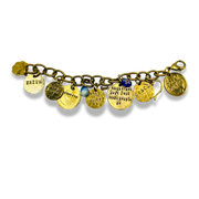 A gold-toned charm bracelet featuring multiple engraved and painted metal charms, including a small blue bead, displayed on a clean white background.