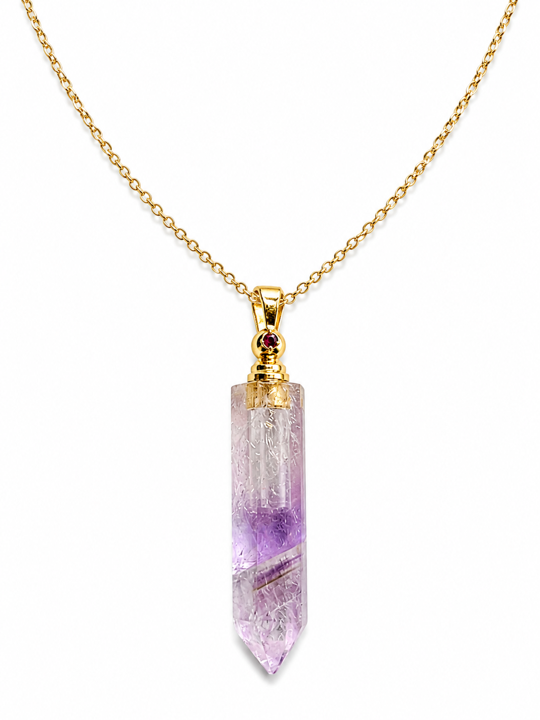 A gold chain necklace featuring a clear quartz point pendant with natural purple and white inclusions, accented by a small round red gemstone at the bail.