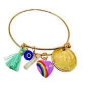 Gold bangle with various charms including a rainbow heart, tassel, and coin on a white background