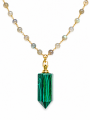 A gold chain necklace featuring a faceted green malachite crystal point pendant, with small round labradorite beads along the chain, shown against a plain white background.