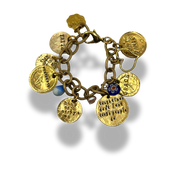 A gold charm bracelet with multiple engraved round medallion charms, a small blue bead, and a floral accent, shown on a white background with a soft shadow.
