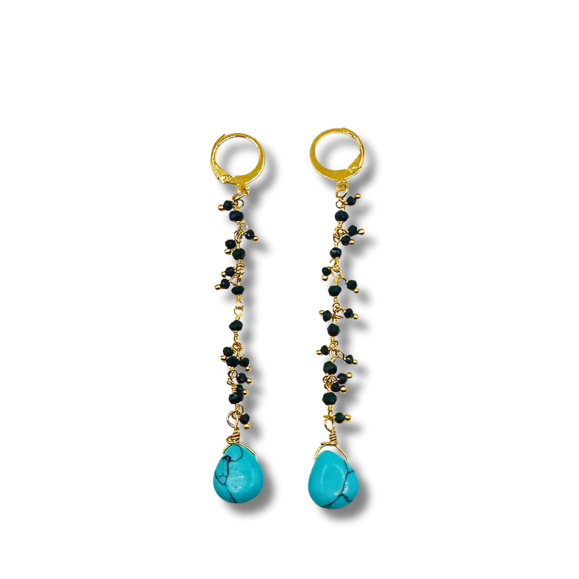 Pair of earrings with turquoise drops and gold hooks on a white background