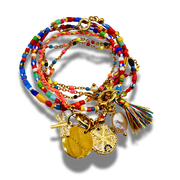 Colorful beaded bracelet with gold charms and tassel on a white background
