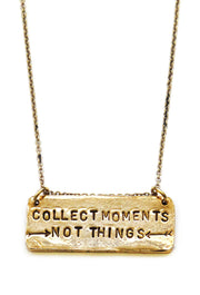 A necklace with a rectangular pendant stamped with the phrase 'Collect Moments Not Things'.